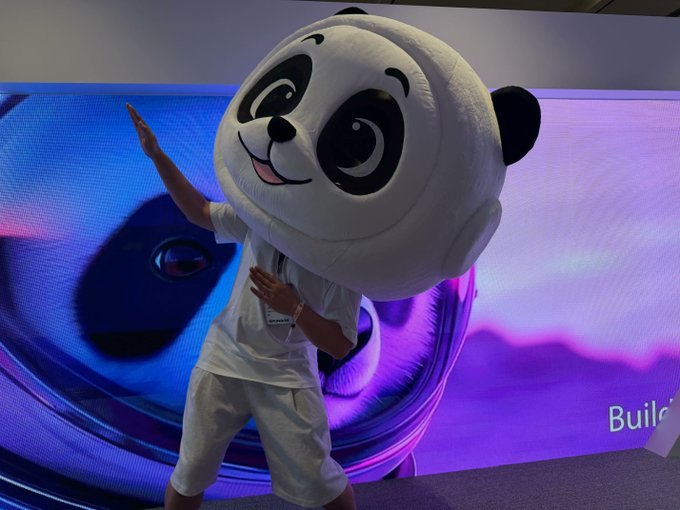0G panda mascot costume waving on a purple stage